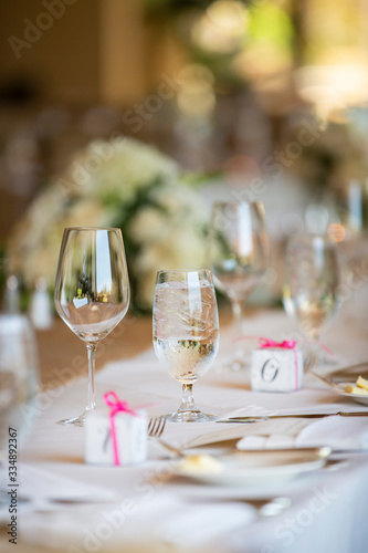 Wedding table setting with ice water filled glass and small gift boxes for the guests