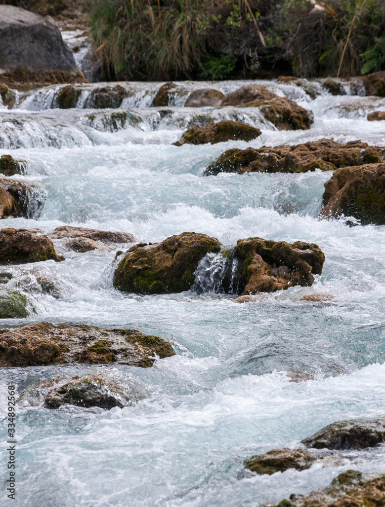 Stones under the surface of a small waterfall with clear turquoise water in Huancaya town, Lima Region, Peru Stones under the surface of a small waterfall with clear turquoise water in Huancaya town, Lima Region, Peru