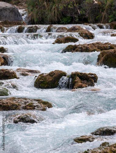 Stones under the surface of a small waterfall with clear turquoise water in Huancaya town  Lima Region  Peru