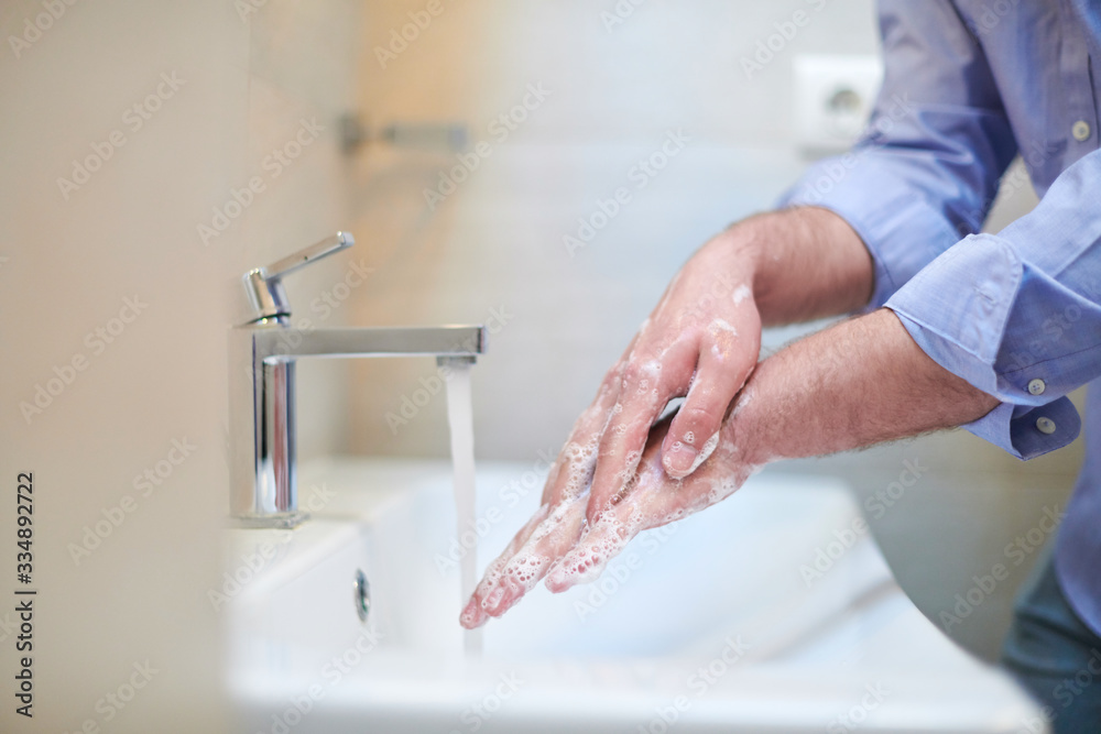 coronavirus male wahing hands in bathroom