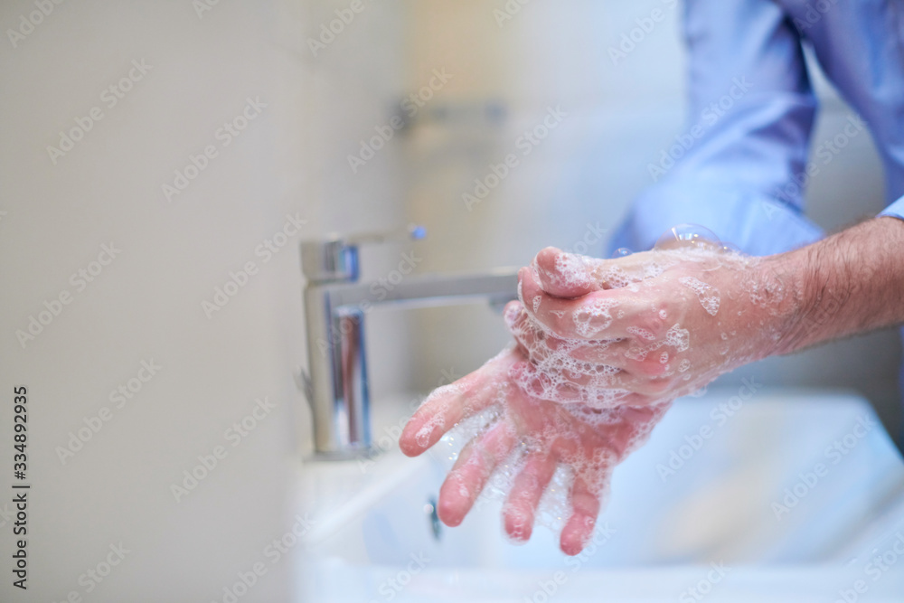 coronavirus male wahing hands in bathroom