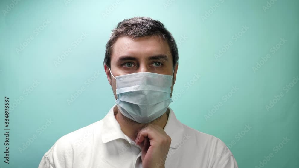 Man in protective medical mask looking in camera on blue background