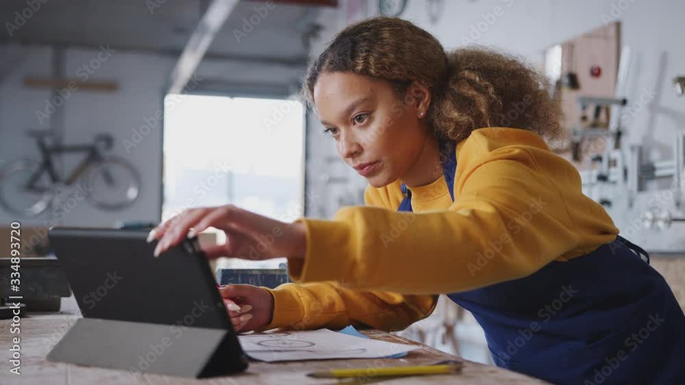 Female business owner in workshop for building bicycles using digital tablet - shot in slow motion