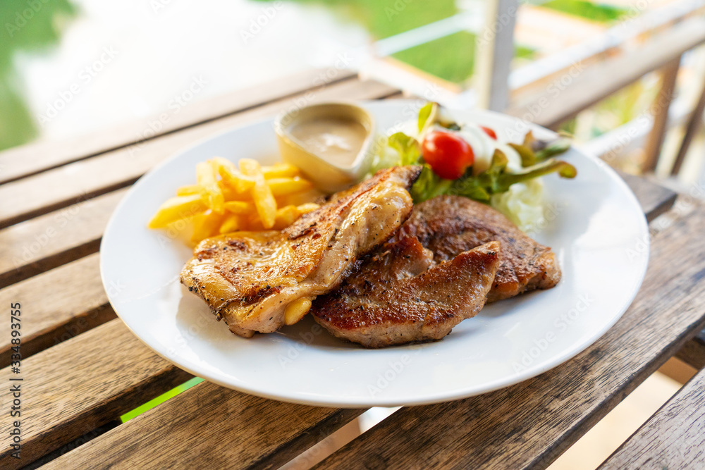 Meat plate of steaks and fries. Chicken and meat on a plate with potatoes in a summer cafe.