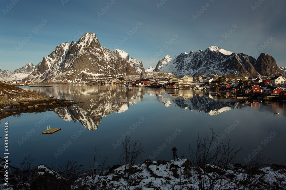View of beautiful Sacrisoya village in winter time with montains in background with light of sunrise. Lofoten, Norway.