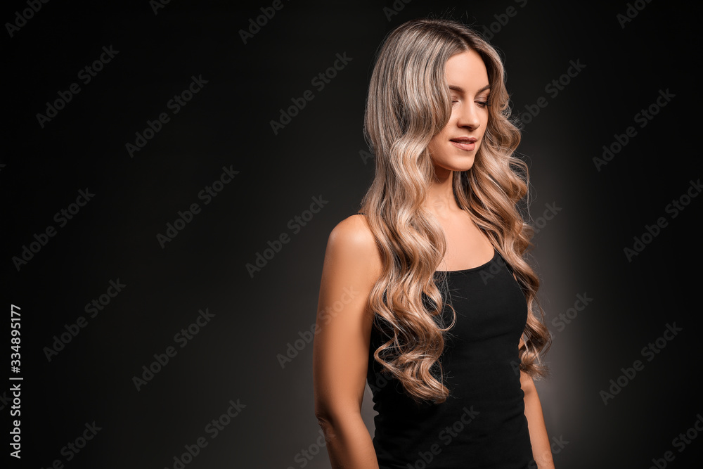 Naklejka premium Beautiful young woman with curly hair on dark background