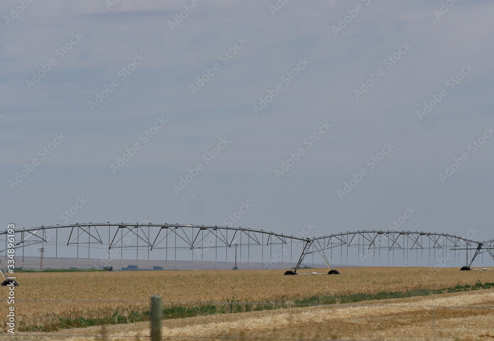 Extended water sprinkler in a farm along the road in Wyoming.
