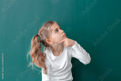 Thoughtful little schoolgirl near blackboard in classroom © Pixel-Shot