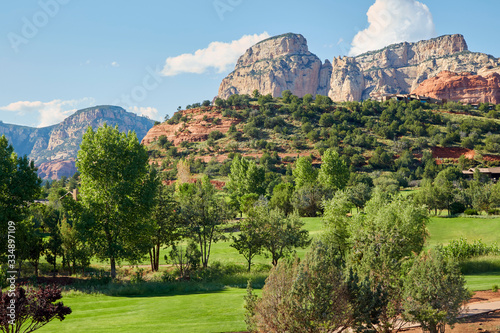 Scenic red rock mountains near Sedona Arizona with green grass and trees on a beautiful summer day