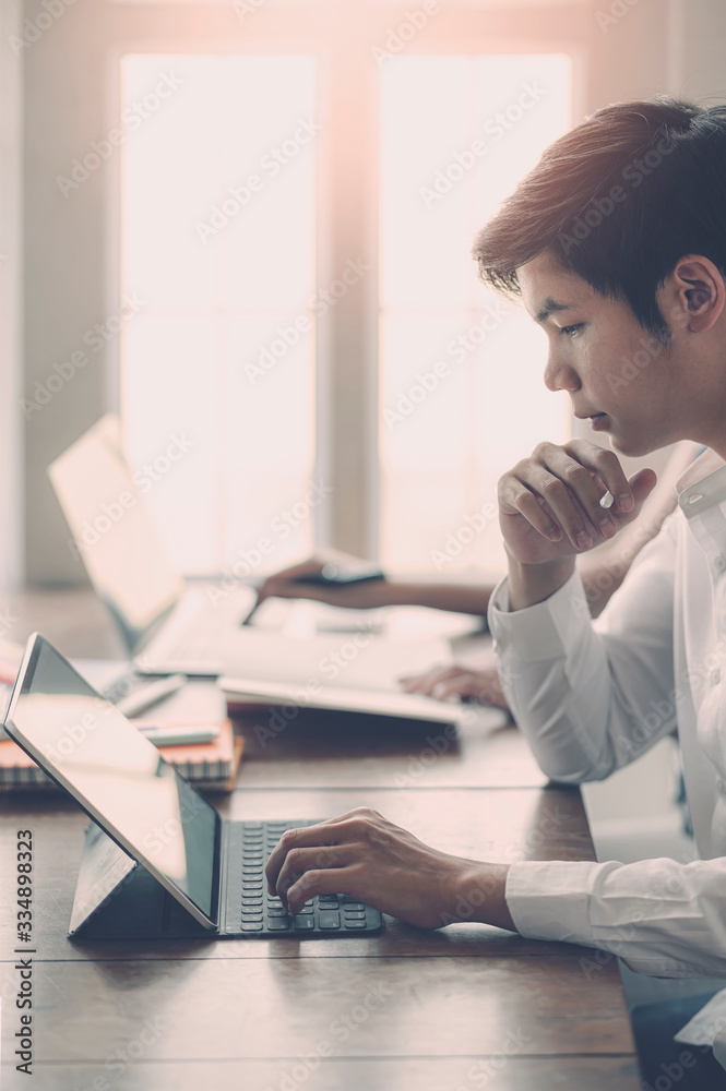 Young businessman working with tablet in modern office, vertical view. Young businessman working with tablet in modern office, vertical view.