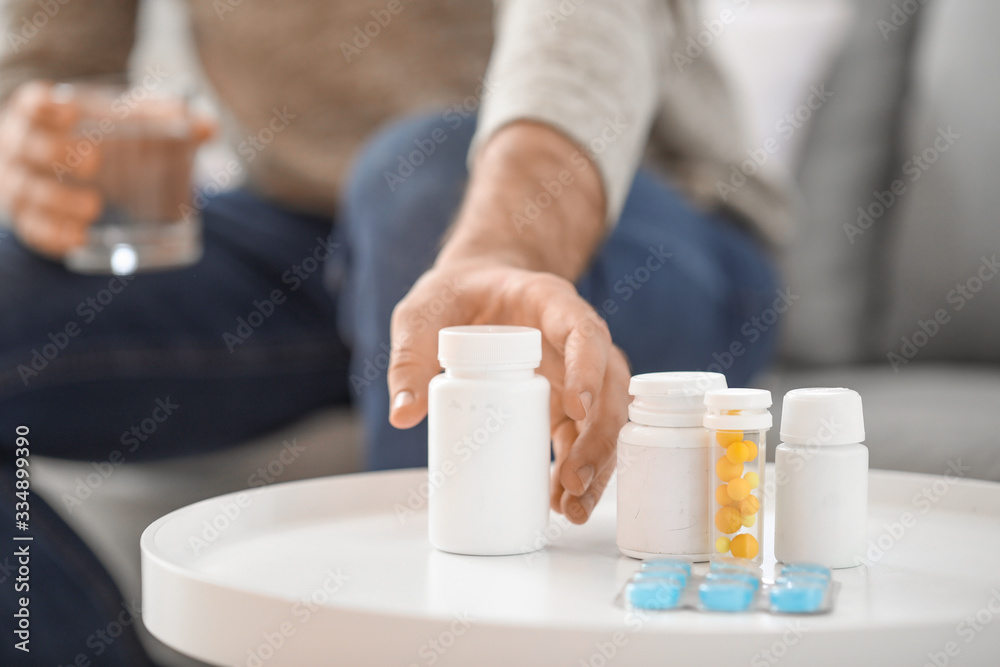 Young man taking medicine from table, closeup