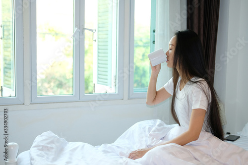 young woman drinking a coffee on the bed