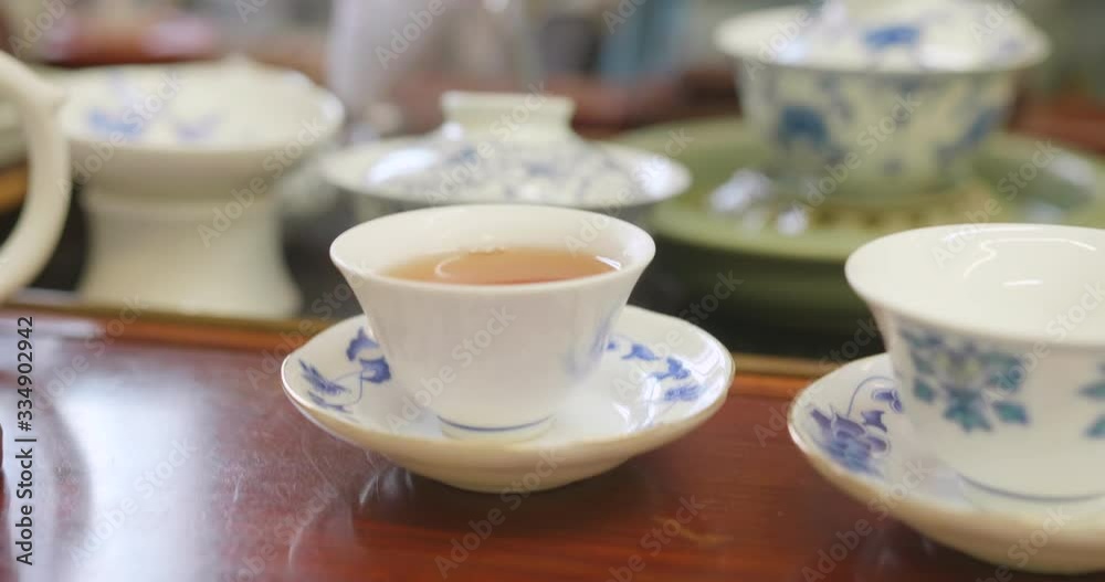 Close up of hands pouring tea from the pitcher into a tea cup. Gong fu cha session, a traditional chinese tea discipline. High dynamic range professional footage. Close up of hands pouring tea from the pitcher into a tea cup. Gong fu cha session, a traditional chinese tea discipline. High dynamic range professional footage.