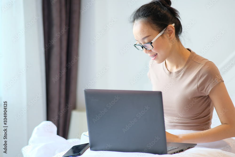 young woman using laptop while lying on her bed and working at home concept young woman using laptop while lying on her bed and working at home concept