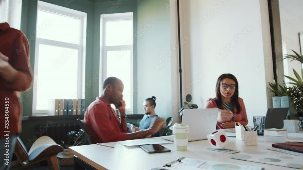 Time lapse of multiethnic mixed-aged colleagues using laptops, speaking on mobile phone, reading documents and having discussions while working in open space office Time lapse of multiethnic mixed-aged colleagues using laptops, speaking on mobile phone, reading documents and having discussions while working in open space office