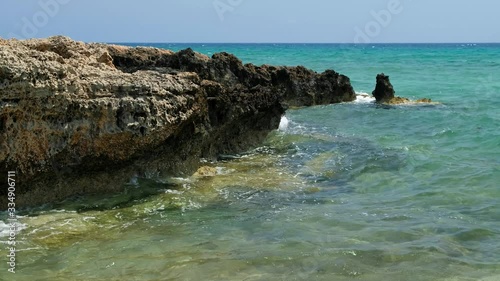 The clear water and surf waves near the rocky shore of the Ayia Thekla beach. Cyprus photo