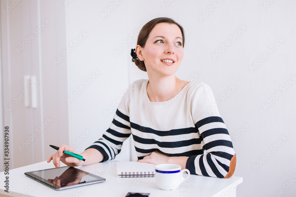 Portrait of smiling pretty young business woman sitting on workplace, light white background, space for text