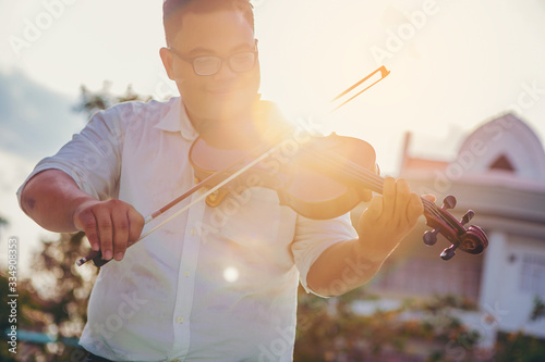 Fat musician man is practicing the violin playing with the melodiousness at the sunset. Selected focus. photo