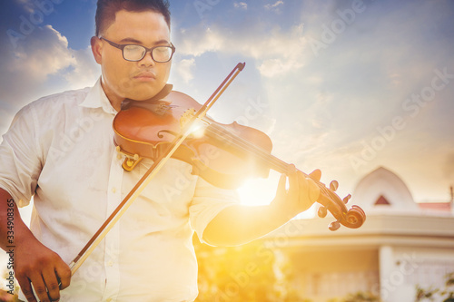 Fat musician man is practicing the violin playing with the melodiousness at the sunset. Selected focus. photo