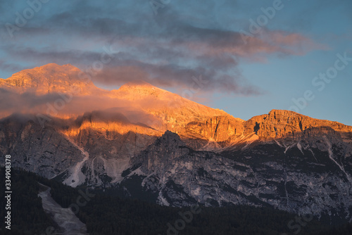 Morning sunlight illuminating the rocky mountain peaks of The Dolomites mountain ranges at sunrise. A scenic view taken from the town of Cortina in Italy
