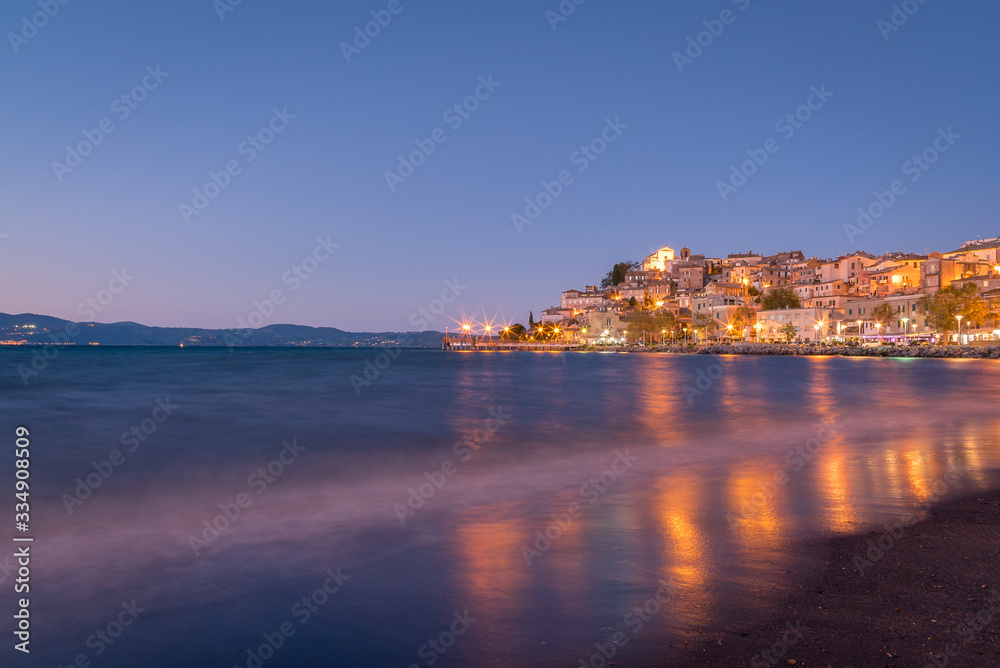 Colourful reflections of lights on the water from the town of Anguillara Sabazia in Italy