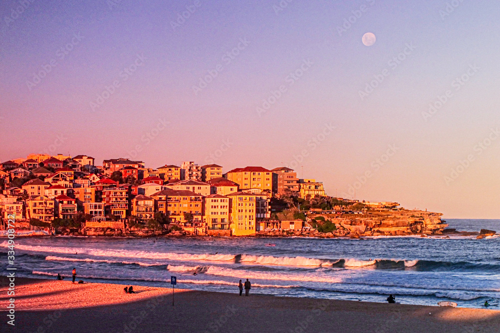 Obraz premium moon rises over north bondi at sunset purple blue pink