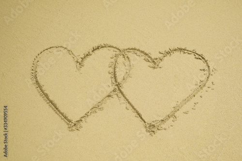 Two hearts drawn on the sand beach representing love, valentine, romance.
