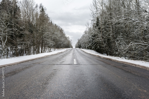 Winter asphalt road through the forest, standing, trees under a layer of snow © Aliaksei