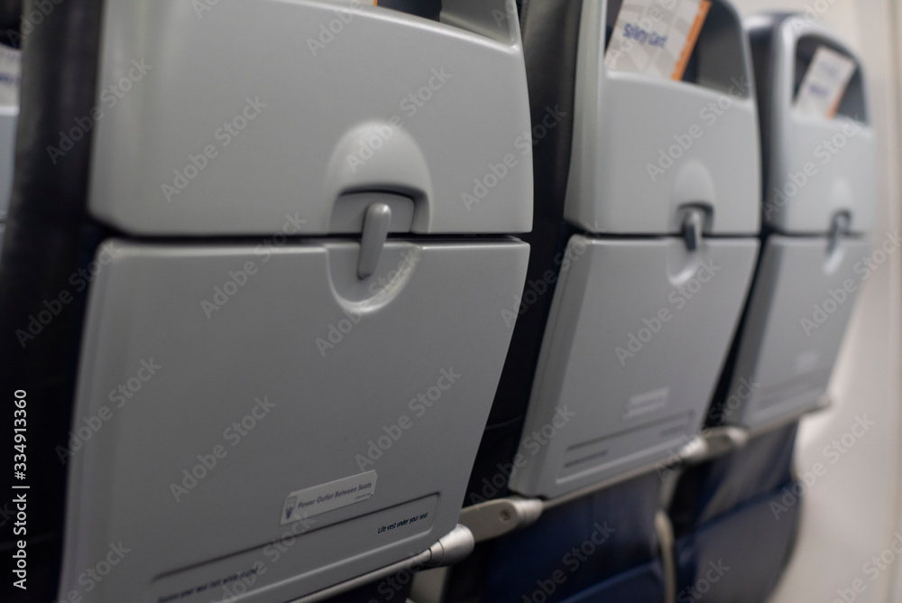Row of airplane tray tables on seatbacks of a commercial aircraft