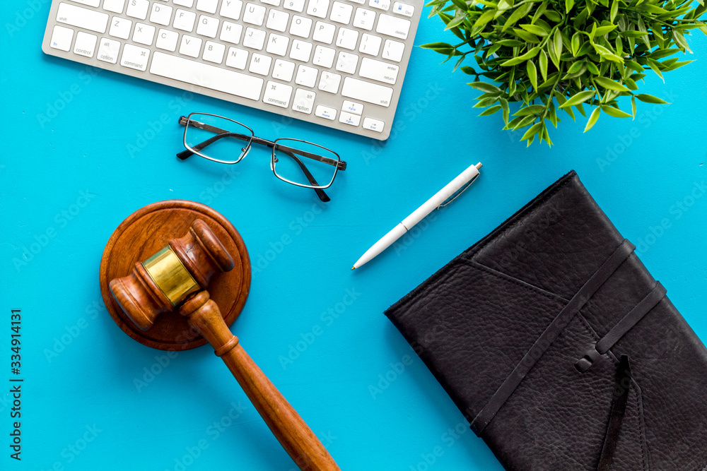 Judge gavel neart documents and keyboard - desk of contemporary lawyer - on blue background top-down Judge gavel neart documents and keyboard - desk of contemporary lawyer - on blue background top-down