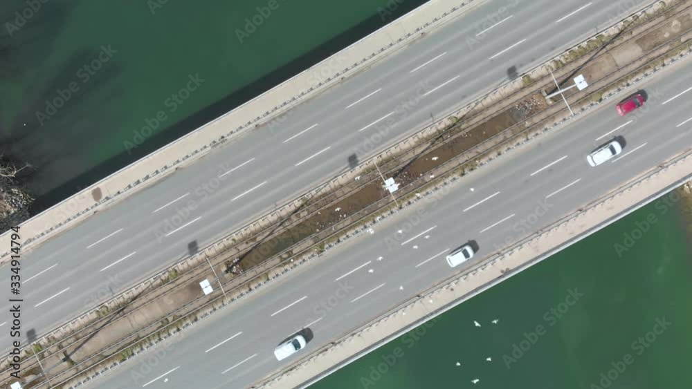 Aerial top down View of high way bridge over the ocean see with slow motion of urban traffic car and flock of white birds Aerial top down View of high way bridge over the ocean see with slow motion of urban traffic car and flock of white birds