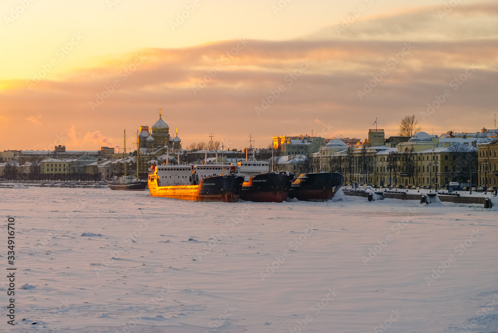 Winter sunset view of the Big Neva and the embankment of Lieutenant Schmidt from the Annunciation (Blagoveshchensky) bridge with ships, St. Petersburg, Russia