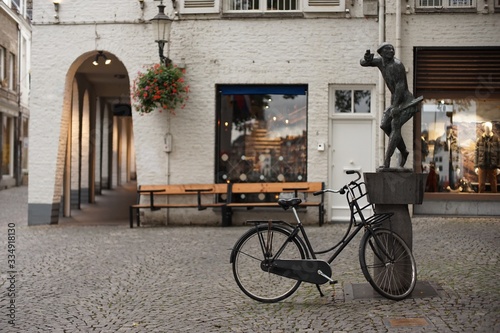 old bicycle parks on the street beside a sculpture in front of a shop