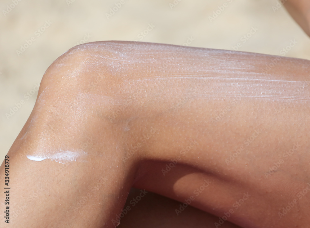 Fototapeta premium The girl is applying sunblock to her legs