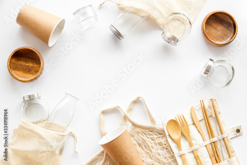 Paper glass, glass jar, wooden tableware on white desk, top view. Eco friendly packaging for take away copy space