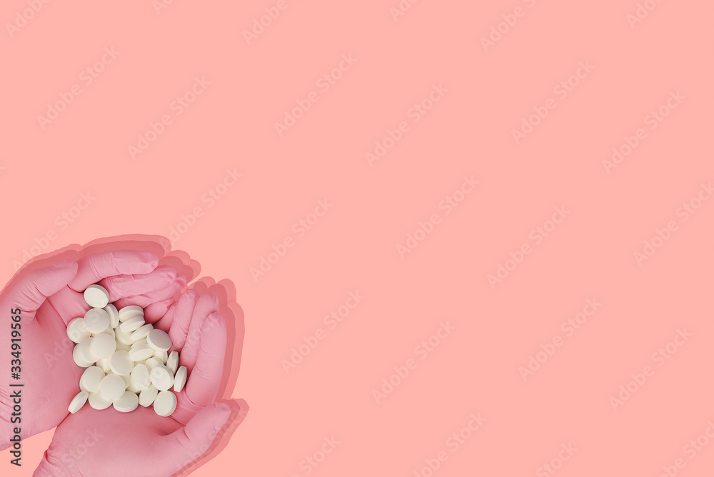 Female hands in pink protective rubber medical gloves holdings white pills on a pink background. Vitamins in the hands. Copy space. Female hand holding a medicine, Woman hands with pills . 