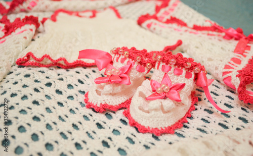 Close view of cute handmade knitted white booties with pink border for a newborn girl