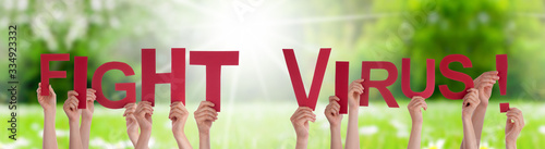 People Hands Holding Colorful English Word Fight Virus. Sunny Green Grass Meadow As Background