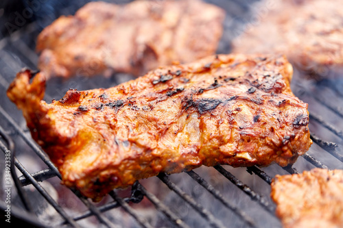 cooking, culinary and food concept - close up of barbecue meat roasting on brazier grill outdoors