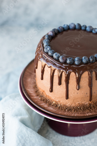 Chocolate birthday cake with blueberries and chocolate icing on a light background