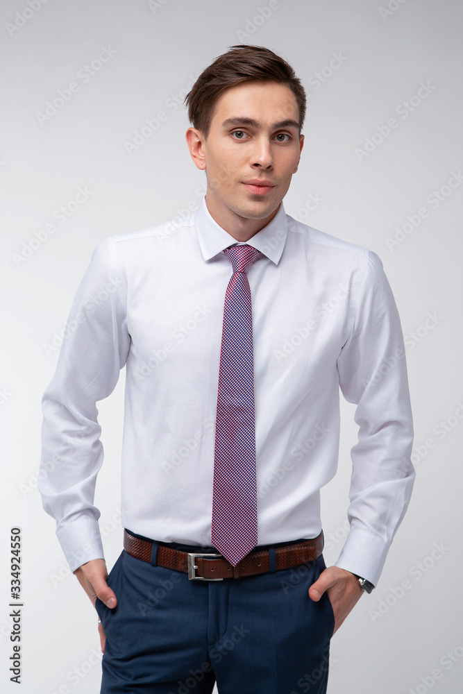 Fototapeta premium Young, handsome man in a white shirt with a tie on a white background in studio