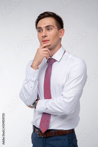 Young, handsome man in a white shirt with a tie on a white background in studio