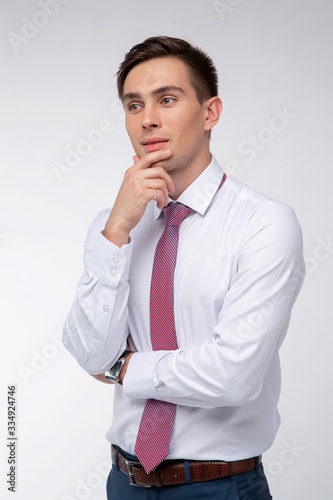 Young, handsome man in a white shirt with a tie on a white background in studio