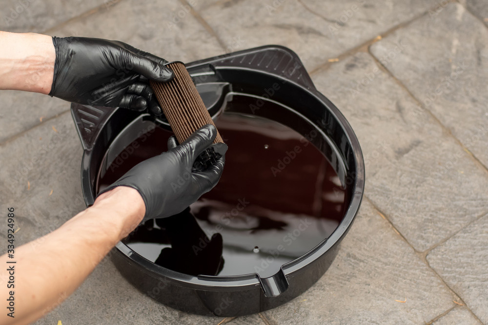 Used drained motor oil in a black tray and used oil filter. DIY change