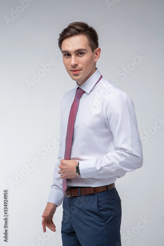 Young, handsome man in a white shirt with a tie on a white background in studio