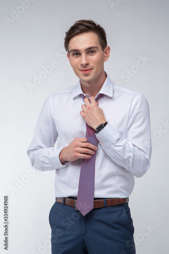 Young, handsome man in a white shirt with a tie on a white background in studio