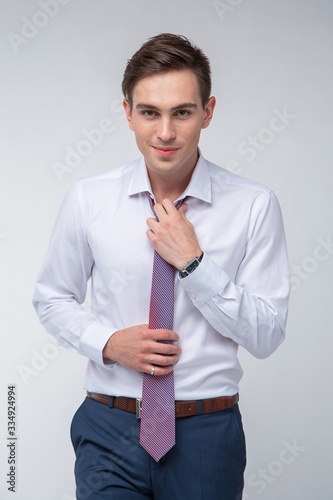Young, handsome man in a white shirt with a tie on a white background in studio