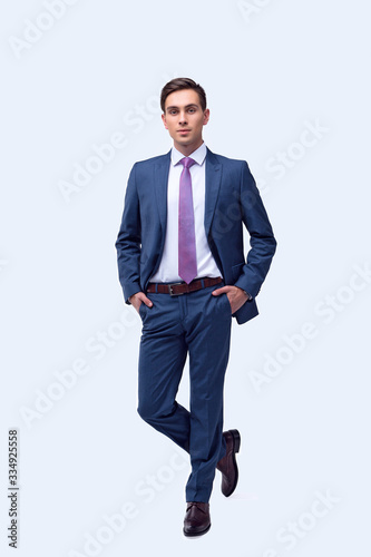 Young, handsome man in a blue suit in a white shirt with a tie on a white background in studio