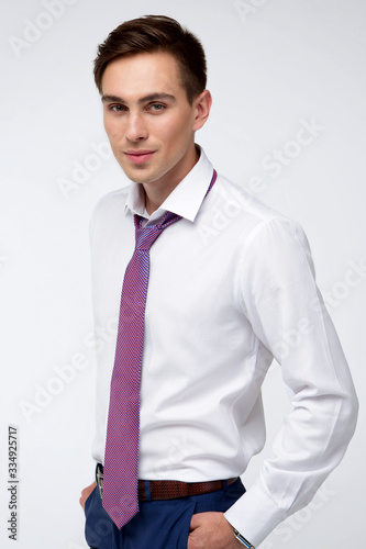 Young, handsome man in a white shirt with a tie on a white background in studio
