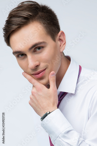 Young, handsome man in a white shirt with a tie on a white background in studio